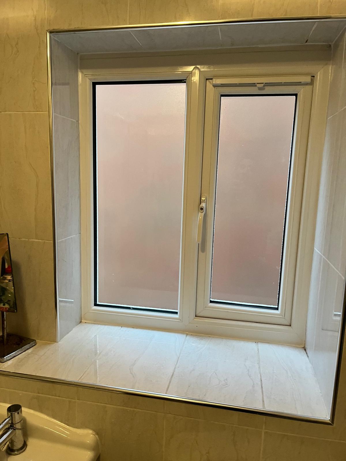 Frosted bathroom window installed in a marble-tiled bathroom